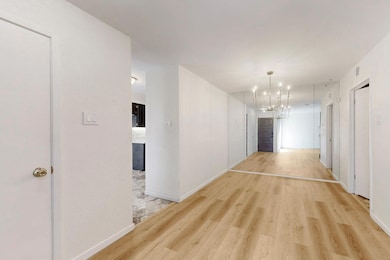 Hall with light wood-style flooring, a chandelier,