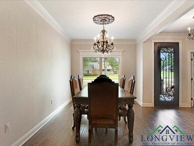 Dining space with a chandelier, wood finished floors, crown molding, and a textured wall
