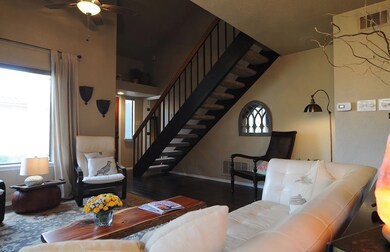 Living room featuring healthy amount of natural light, wood finished floors, ceiling fan, and stairway