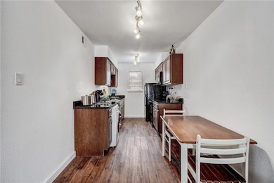 Kitchen with dark countertops, dark wood-type flooring, and stainless steel microwave