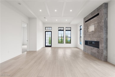 Unfurnished living room featuring light hardwood / wood-style floors, beamed ceiling, and a fireplace
