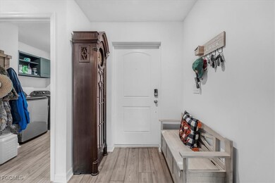 Hall with light wood-style floors and washer / dryer