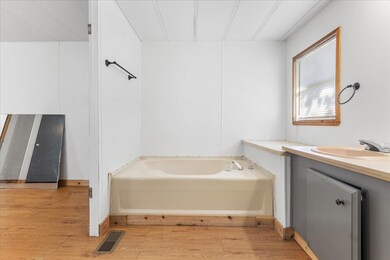 Full bathroom with vanity, a bath, and light wood-type flooring