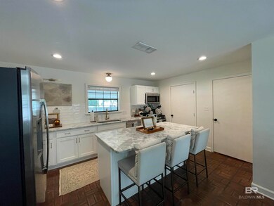 Kitchen with a sink, visible vents, brick floor, and stainless steel appliances