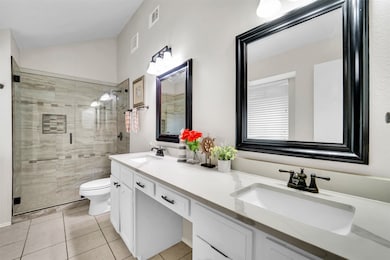 Bathroom with a shower stall, double vanity, light tile patterned flooring, and vaulted ceiling