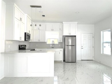 Kitchen with tasteful backsplash, white cabinetry, appliances with stainless steel finishes, light stone countertops, and recessed lighting