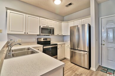 The kitchen has many cabinets, a breakfast bar, pl