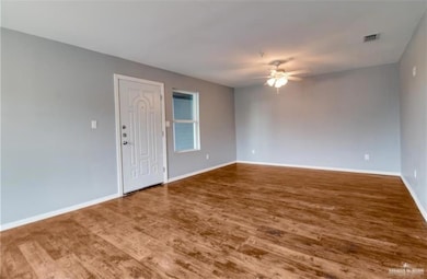 Unfurnished room featuring visible vents, baseboards, a ceiling fan, and wood finished floors