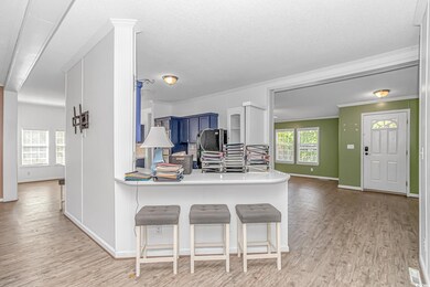 Kitchen featuring light wood-style floors, a breakfast bar, baseboards, crown molding, and a peninsula