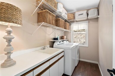 Large main floor laundry with wood flooring, cabinetry, laundry sink and folding area.