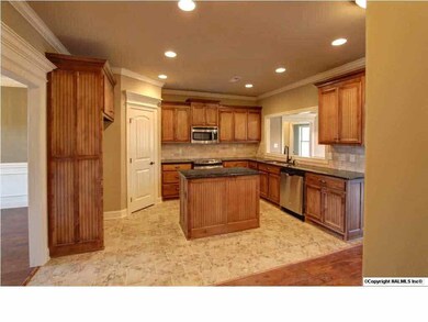 Kitchen with custom cabinets, granite counter tops, island,, tile back splash, tile floors, stainless appliances, recessed lights.