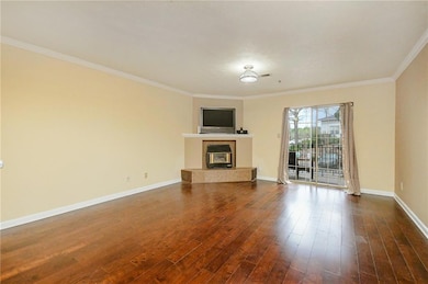 Unfurnished living room featuring a tiled fireplace, ornamental molding, and dark wood finished floors