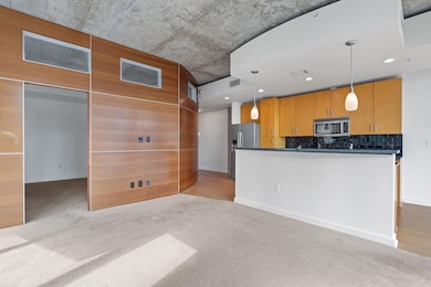 Kitchen with decorative light fixtures, open floor plan, appliances with stainless steel finishes, light colored carpet, and backsplash