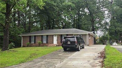 Single story home featuring driveway, brick siding, and a front yard