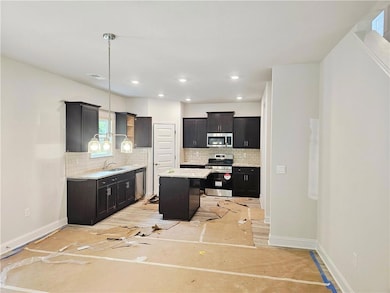 Kitchen featuring stainless steel appliances, a sink, tasteful backsplash, baseboards, and recessed lighting