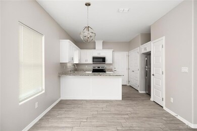 Kitchen featuring stainless steel appliances, a peninsula, a chandelier, and light wood-style floors