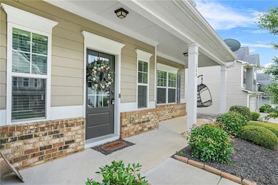 Doorway to property with covered porch and brick siding
