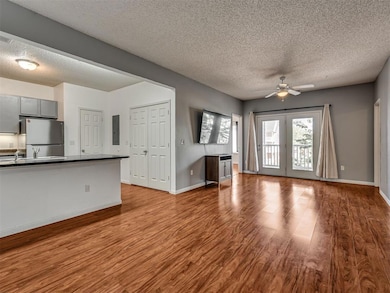 Unfurnished living room featuring a textured ceiling, wood finished floors, ceiling fan, and electric panel