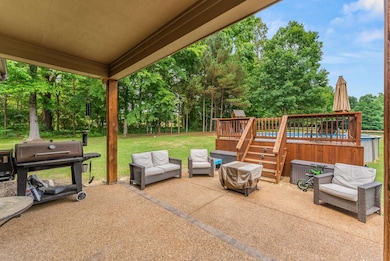 View of patio / terrace featuring a jacuzzi, a deck, an outdoor hangout area, area for grilling, and view of wooded area
