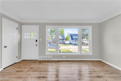 Foyer entrance with light wood finished floors and baseboards