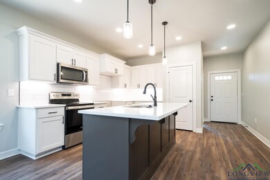 Kitchen with white cabinets, appliances with stain