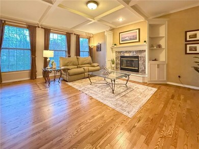 Living room featuring light hardwood / wood-style floors, ornamental molding, a tile fireplace, and coffered ceiling
