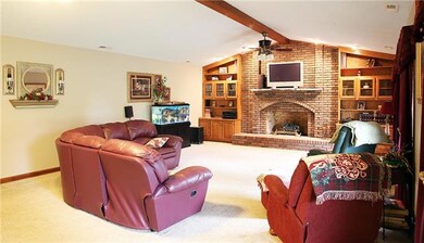 The great room is very spacious and features custom built-ins, a gas log fireplace with large brick hearth, and an impressive wooden beam that runs the length of the ceiling.