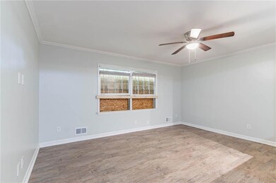 Empty room featuring wood finished floors, a ceiling fan, and ornamental molding