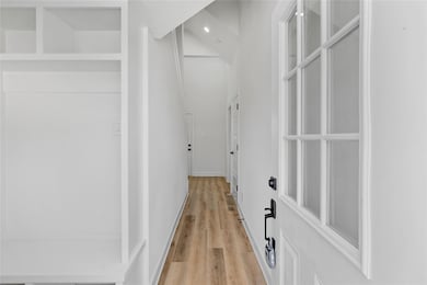 Sleek foyer defined by soaring ceilings, crisp white walls, and wide-plank wood flooring that highlights the home’s streamlined architectural flow.