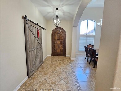 Entryway with arched walkways, a barn door, a chandelier, and light tile patterned flooring
