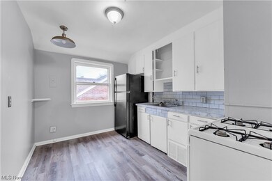 Kitchen with backsplash, light wood-type flooring, white cabinets, refrigerator, and white stove