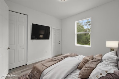Bedroom with light wood finished floors and basebo