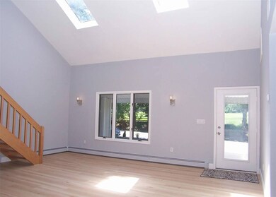 Unfurnished living room with a skylight, light wood finished floors, plenty of natural light, and high vaulted ceiling