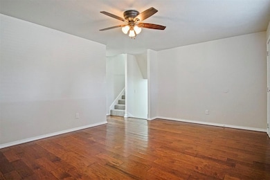 Unfurnished room featuring dark wood-style floors, stairs, and ceiling fan
