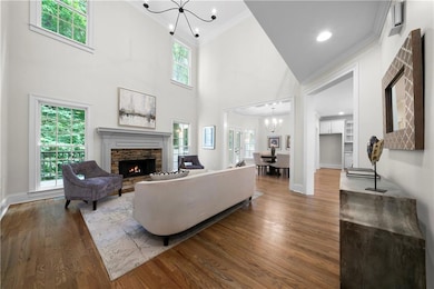 Living area featuring a chandelier, crown molding, wood finished floors, a high ceiling, and a fireplace