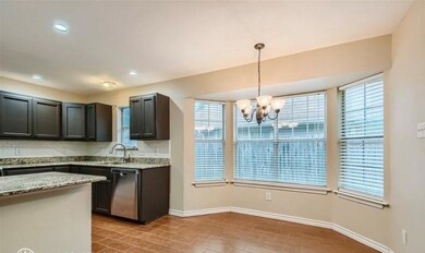 Kitchen with a wealth of natural light, hanging light fixtures, dishwasher, and light stone counters