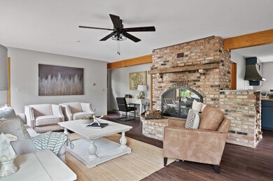 Spacious sun-filled living room with a cozy wood-burning fireplace and another spectacular view of the lake.