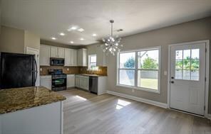 Kitchen with white cabinetry, black fridge, light 