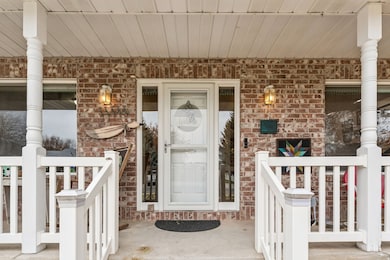 Entrance to property with covered porch and brick siding
