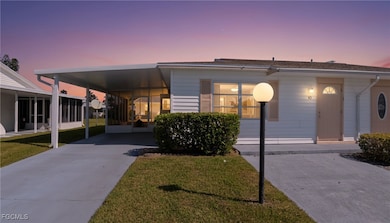 View of front of house featuring an attached carport, a front yard, and concrete driveway