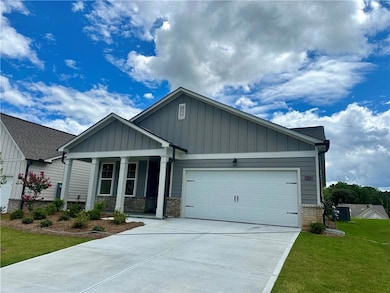 Craftsman-style home featuring a porch, an attached garage, board and batten siding, concrete driveway, and a front yard