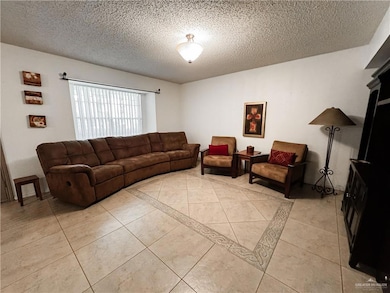 Living area featuring light tile patterned floors and a textured ceiling