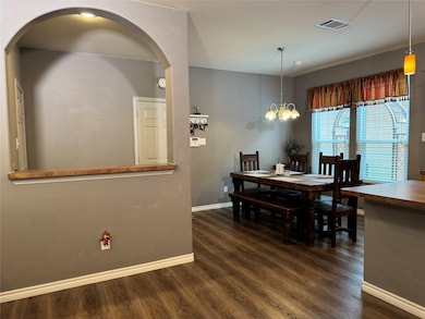Dining space featuring arched walkways, LVP floors floors, and a chandelier
