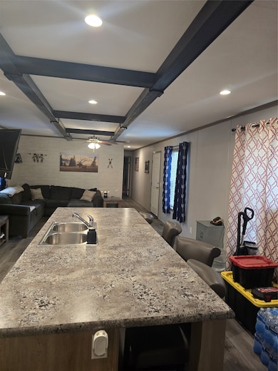 Kitchen featuring open floor plan, beamed ceiling, an island with sink, a breakfast bar area, and recessed lighting