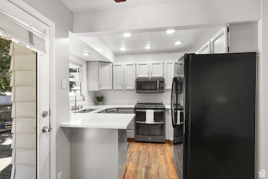 Kitchen with freestanding refrigerator, range with two ovens, recessed lighting, light wood-type flooring, and stainless steel microwave