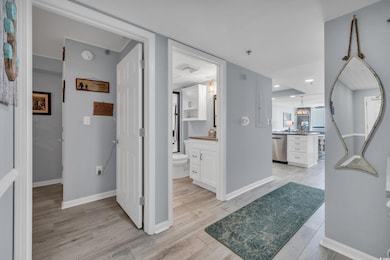 Corridor with light wood-style floors, baseboards, and a chandelier