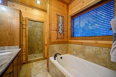 Bathroom featuring vanity, separate shower and tub, and wood walls