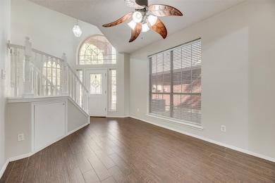 Entryway with stairs, dark wood-style flooring, ceiling fan, and high vaulted ceiling