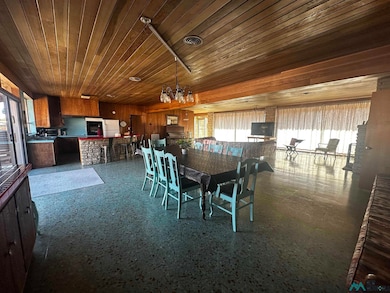 Dining area featuring plenty of natural light, wooden ceiling, wood walls, and light aggregate flooring