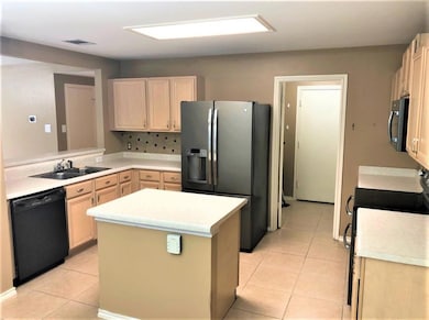 Kitchen featuring black appliances, light tile patterned floors, light brown cabinetry, and light countertops